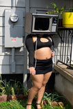 woman wearing a black outfit with cut-out design, standing outdoors with TV head